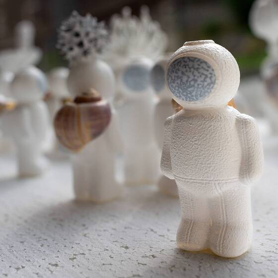 UStronaut mit blauem Auge im Visier von hinten, im Vordergrund unscharfe Figuren.