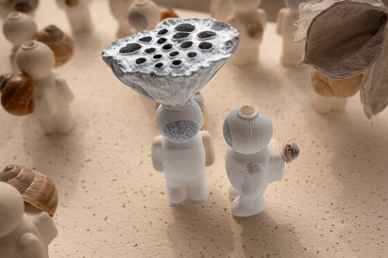 Zwei UStronauts auf einem Tisch, im unscharfen Hintergrund eine Lotusform.