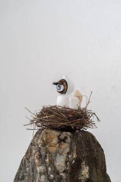 UStronaut mit blauem Auge im Visier sitzt in einem Nest auf einem Stein.