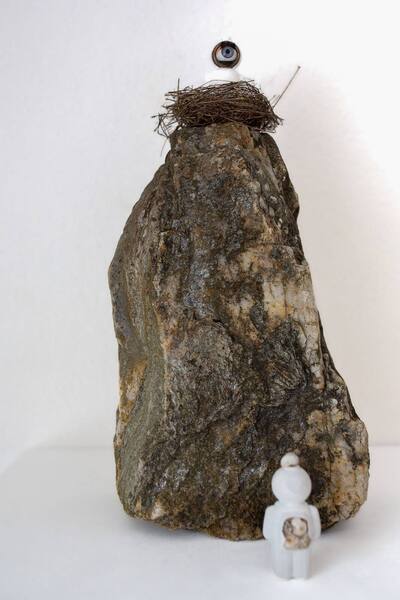 Grosser Stein mit einem Nest und einem UStronaut obenauf, unten steht eine kleine Figur.