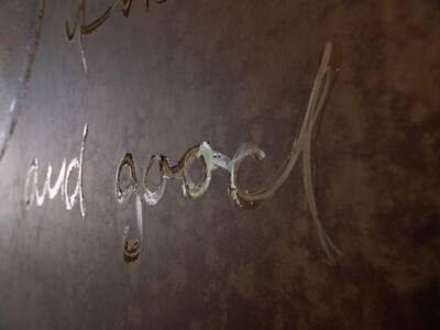 Close-up of a dark metal surface with engraved handwriting.