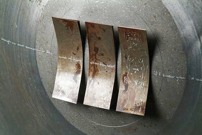 Three curved rust plates with characters on a round metal bowl.