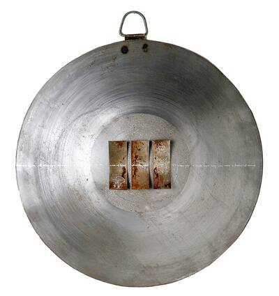 Round, silvery metal bowl with three curved rust plates in the centre.