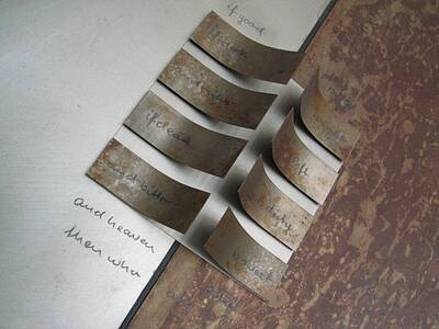 Curved rust plates with handwritten words on a metal surface.