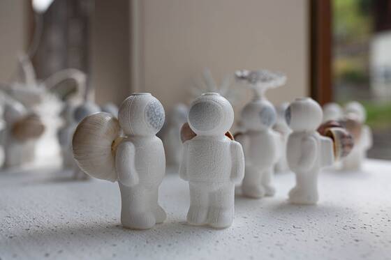 UStronauts from behind with snail shells, a window with a green view behind them.