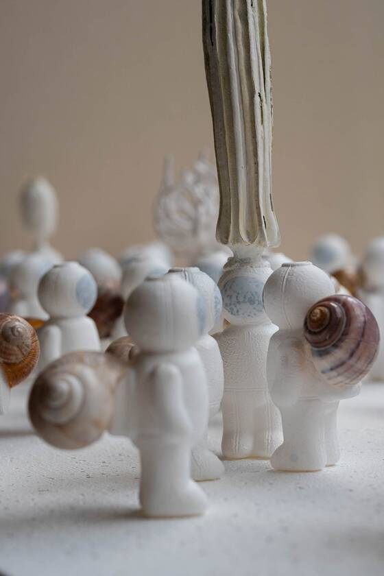 White UStronaut figures with snail shells on their backs; a pale grey stem rises behind them.