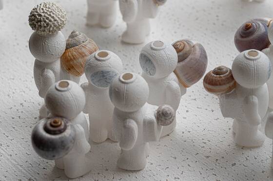 Group of white UStronauts with snail shells, seen from above on a white speckled surface.