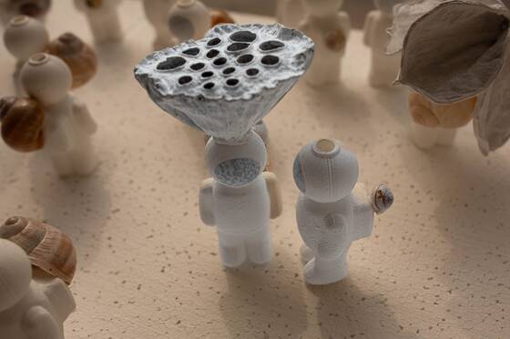 UStronaut with a lotus pod on its head, beside a figure holding a small snail.