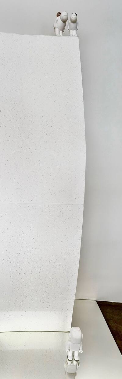 Narrow white plinth with two tiny UStronauts at the very top.