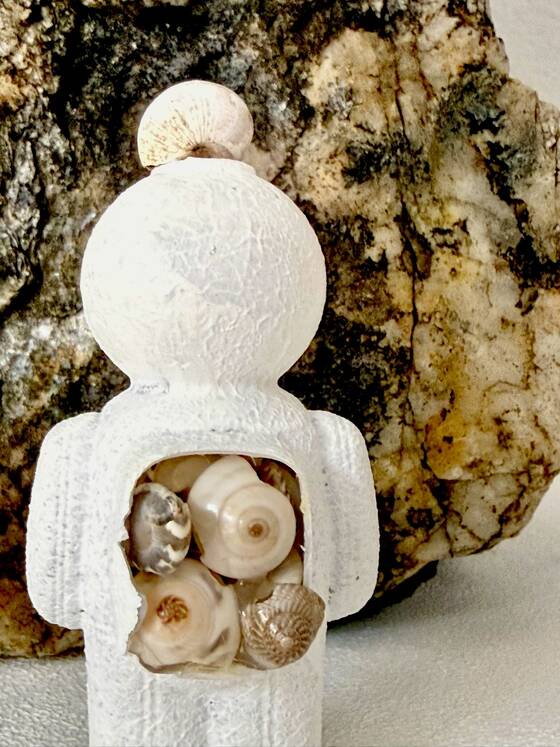 White figure in front of a stone, several snail shells visible inside its chest.