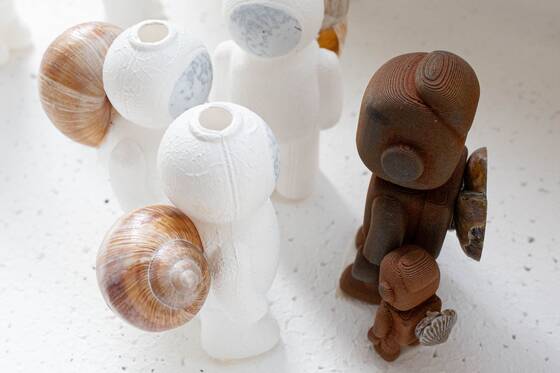 White UStronauts with snail shells and a rust-brown RAWbot carrying a metal disc on its back.