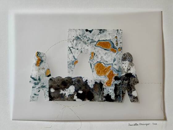Three paper figures with golden patches around a dark, textured area.