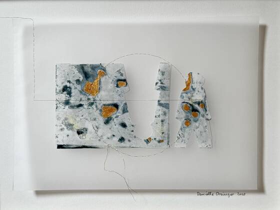 Two paper figure shapes with blue-and-white patterns and golden patches on a translucent support, a fine thread forming a circle.